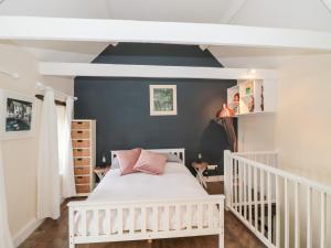 1 dormitorio con cuna blanca y pared azul en Long Cottage en Bath