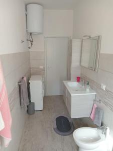 a white bathroom with a sink and a toilet at Brezza Marina a 30 mt dalla spiaggia in Marina di Castagneto Carducci