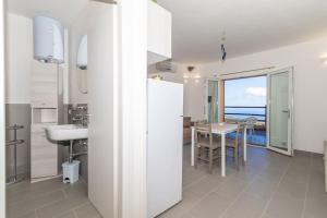 a white bathroom with a sink and a table at Appartamento monolocale vista mare FT3 in Cascabraga