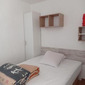 a small bedroom with a white bed and a cabinet at Empuriabrava Vue Mer in Empuriabrava