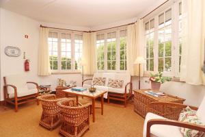 a living room with rattan furniture and windows at GRANDMA BAY HOUSE in São Martinho do Porto