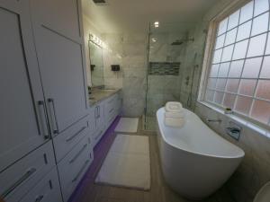 Baño blanco con bañera y lavamanos en Cozy modern house - Near SXSW and other events en Austin
