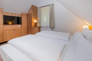 1 Schlafzimmer mit 2 weißen Betten und einem TV in der Unterkunft Cottages, turf house in Torfhaus