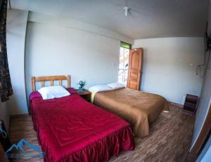 2 camas en una habitación con manta roja en Chacraraju Hostel, en Huaraz