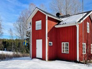 a red barn with a white door in the snow at Holiday home TÖCKSFORS III in Töcksfors