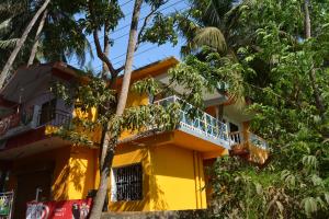 a yellow building with a balcony and trees at chill out home morjim in Morjim