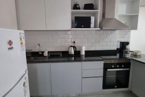 a kitchen with white cabinets and a black stove top oven at Elegante y fino departamento a estrenar! in La Mercedes