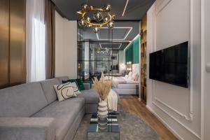 a living room with a gray couch and a chandelier at Dream Fiumara Apartments in Rijeka