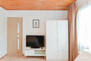 a living room with a television and a white cabinet at RAMYBĖS OAZĖ 2 in Šventoji