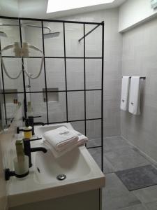 a bathroom with a sink and a shower with towels at Nica Wood in Sremska Kamenica