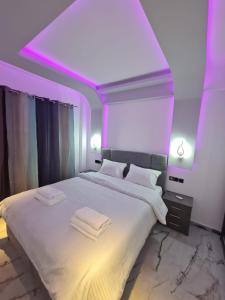 雅典的住宿－Luxury apartment in Attiki，一间卧室配有一张白色大床和紫色灯