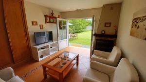 a living room with a couch and a tv and a table at Apartamentos El Otero de Cudillero in Soto de Luiña