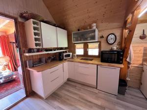 a kitchen with white cabinets and a clock on the wall at Chalet Vue Montagne 6 personnes proche Sanctuaire de La Salette in La Salette-Fallavaux