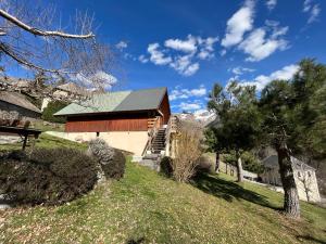 un fienile con un tetto verde su una collina con alberi di Chalet authentique a La Salette-Fallavaux