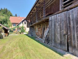 a large wooden barn with a grass yard next to it at Domačija pri Ivankovih in Osilnica