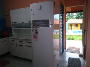 a white refrigerator in a kitchen next to a door at Sítio Descanso E Natureza Igarapé - 20km Inhotim in Igarapé