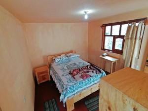een kleine slaapkamer met een bed en een raam bij Hostal Doña Clarita & Vegetarían Food in Chugchilán
