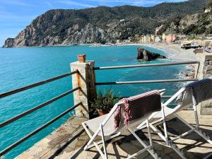 a pair of chairs sitting on a balcony overlooking a beach at La Casa Del Doganiere in Monterosso al Mare