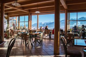 a restaurant with tables and chairs with mountains in the background at Almcafe Schnakenhöhe in Maria Rain