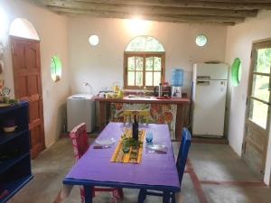 eine Küche mit einem lila Tisch und einem Kühlschrank in der Unterkunft Casa de montaña placentera en la naturaleza con vista espectacular en Traslasierra in Cordoba