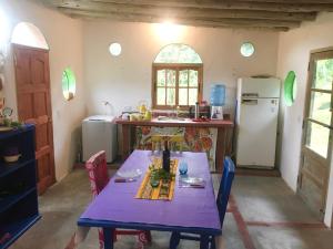 cocina con mesa púrpura y nevera en Casa de montaña placentera en la naturaleza con vista espectacular en Traslasierra en Córdoba