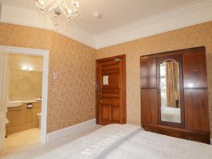 a bedroom with a bed and a bathroom with a chandelier at Ledgowan Lodge Hotel in Achnasheen
