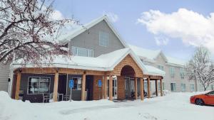 a house covered in snow with a red car in front at Country Inn & Suites by Radisson, Detroit Lakes, MN in Detroit Lakes