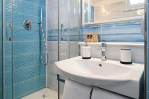 La salle de bains blanche est pourvue d'un lavabo et d'une douche. dans l'établissement L'Antico Portone B&B, à Palinuro