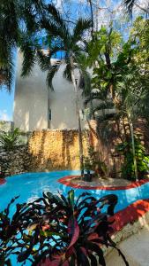 a swimming pool with palm trees in front of a building at Hotel B&B - 5th Avenue in Playa del Carmen