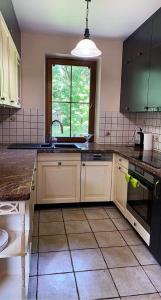 uma cozinha com armários brancos, um lavatório e uma janela em Uroczy dom Wszebory 