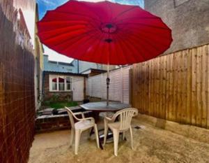 stół i krzesła z czerwonym parasolem na patio w obiekcie 64 Bath Road - ground floor w mieście Cheltenham