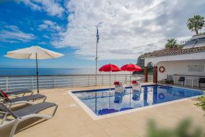 Una piscina con sillas y sombrillas y el océano. en Villa Beach Club, en Santa Cruz