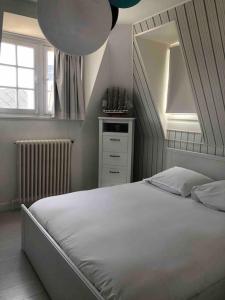 a bedroom with a large white bed and a mirror at Villa Le Nid in Deauville