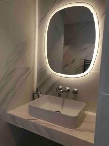 La salle de bains est pourvue d'un lavabo et d'un miroir. dans l'établissement Villa Le Nid, à Deauville