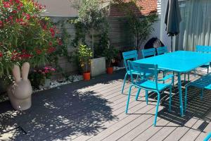 une table bleue et des chaises sur une terrasse fleurie dans l'établissement Villa Le Nid, à Deauville