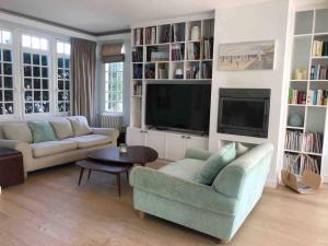 a living room with two couches and a tv at Villa Le Nid in Deauville