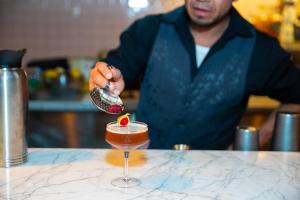 Ein Mann bereitet einen Drink in einem Cocktailglas vor. in der Unterkunft SLS Hotel, a Luxury Collection Hotel, Beverly Hills in Los Angeles