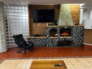 sala de estar con chimenea, silla y TV en Infinity Villa en Buşteni