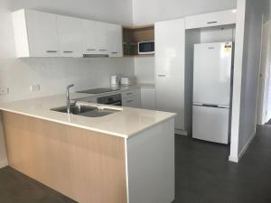 a white kitchen with a sink and a refrigerator at Location, location, location - ground floor in Brisbane