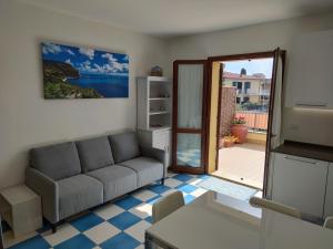 sala de estar con sofá y puerta a un patio en Appartamento L'Azalea - a due passi da Numana con grande terrazzo e piscina condominiale stagionale, en Sirolo