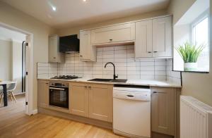 a kitchen with white cabinets and a sink and a dishwasher at Stunning luxury 3 bed house with garden in North Leeds in Moortown