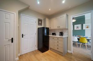 La cuisine est équipée de placards blancs et d'un réfrigérateur noir. dans l'établissement Stunning luxury 3 bed house with garden in North Leeds, à Moortown