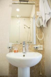 een badkamer met een witte wastafel en een spiegel bij Town Gates Hotel in Baku