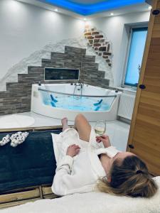 una mujer acostada en una cama frente a una bañera en Luxe Apartments en Ljutomer