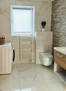 a white bathroom with a toilet and a window at Luxe Apartments in Ljutomer