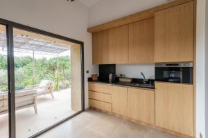 a kitchen with wooden cabinets and a sliding glass door at Bastidon du Domaine de La Julienne in Tourves