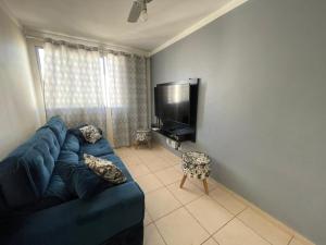uma sala de estar com um sofá azul e uma televisão em Apartamento - Dois Dormitórios - Todo Equipado em Bauru