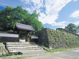 un muro di pietra con scale e un edificio di Hitoyoshi Onsen Hotel Hananoshou - Vacation STAY 40074v a Hitoyoshi