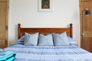 uma cama azul e branca com almofadas azuis e brancas em Cosy Beachside Cottage em Bigbury