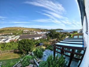 a balcony with a view of a town and the ocean at Cosy Beachside Cottage in Bigbury
